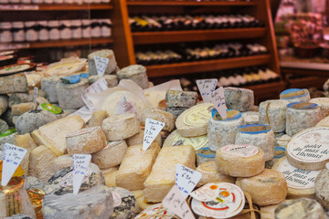 Paris Cheese and Wine Shop with a selection of Camembert, Coulommiers, Munster, Gruyere, Comte, and Parmesan cheeses.