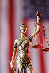 Lady Justice figure holding scales in front of American flag representing law and order