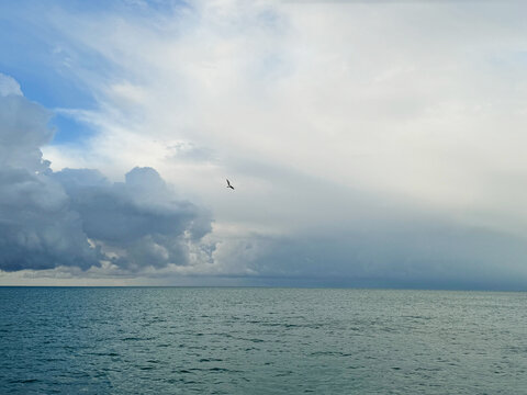 Cloudy sky over calm blue ocean.