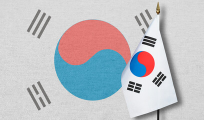 A small South Korea flag with a faint image of the South Korea flag in the background