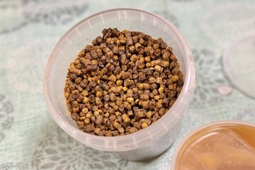 A lot of bee perga as called ambrosia, bee pollen in a plastic container. Top view. Healthy eating. The energy of life. Close-up