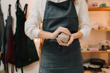 Woman potter works with wet clay in the pottery studio. Girl potter is creating a ceramic ware in...