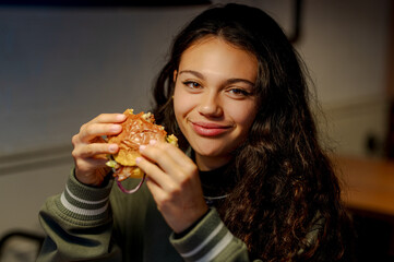 Happy customer eating a hamburger in a fast food restaurant