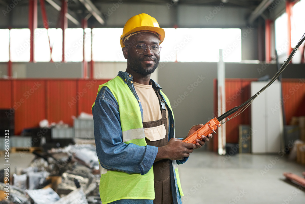 Poster young african american factory engineer with control pad in hands looking at camera during work in w