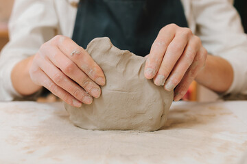 Potter is sculpting wet clay for ceramics products. Hands of a female potter making ceramic clay...
