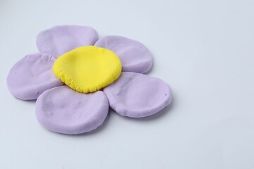 Flower made from play dough on light grey background, closeup. Space for text