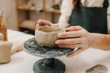 Process of creating ceramic products. Female potter hands shows ceramic bowl ready for firing in a...