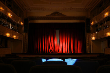 Elegant closed red curtains illuminated by spotlight in theatre