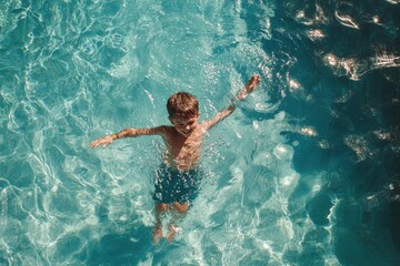 Boy swimming joyfully in clear blue water during a sunny day by the shore
