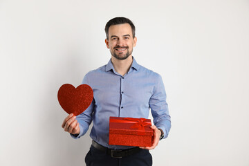 Happy Valentine's Day. Handsome man with paper heart and gift on white background