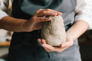 Potter holds a piece of wet clay in their hands, molds it into form. Process of creating ceramic...