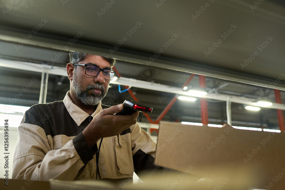 Leinwandbilder mature multiethnic factory worker scanning barcodes on packed cardboard boxes while making revision 