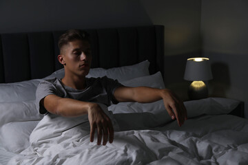 Fototapeta premium Young man suffering from sleepwalking on bed at home