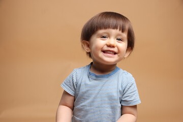 Portrait of adorable little boy on light brown background