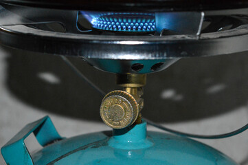 portable gas stove with a blue propane cylinder and a frying pan heating open flam camping...