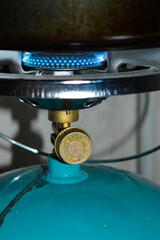 portable gas stove with a blue propane cylinder and a frying pan heating open flam camping...