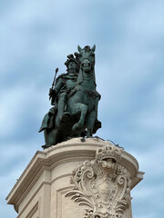 Obraz premium Description (under 200 characters):Low angle shot of the Equestrian Statue of King José I in Lisbon, Portugal, against a cloudy sky. Detailed sculpture atop a decorated arch, showcasing historical