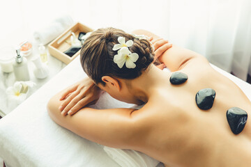 Hot stone massage at spa salon in luxury resort with day light serenity ambient, blissful woman...