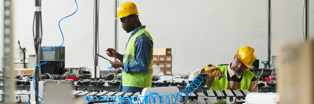 Fototapete Header of two intercultural male professionals looking through document and taking notes and using electric handtool