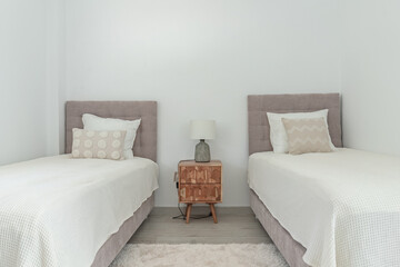 a close up image of two single beds and bedside table in mediterranean holiday home 
