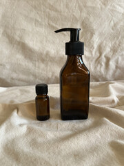 Brown glass bottle for liquid with black pump dispenser and small glass brown bottle with black cap