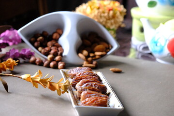 Ramadan iftar table. Dates, green and black olives on the plate. Hazelnuts and almonds. Close-up photos with teapot and floral decor. Islam, muslim, iftar time, worship, prayer. Fasting.