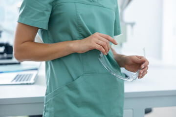 Anonymous woman scientist holding protective glasses for safety at laboratory