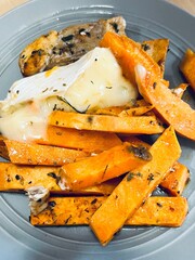 healthy gluten free dinner. Baked sweet potato, fish fillet and melted camembert cheese create a tasty and nutritious meal on a gray plate. side view restaurant