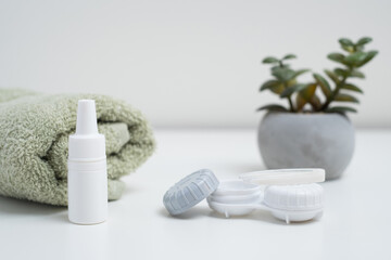 Contact lenses, case and bottle with solution and eye drops on white background. Eye health and care, vision, ophthalmology concept, close-up