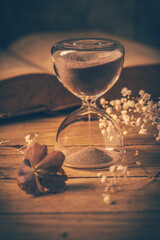 Hourglass with old book. Symbol of passing time and memories. Conceptual vintage image
