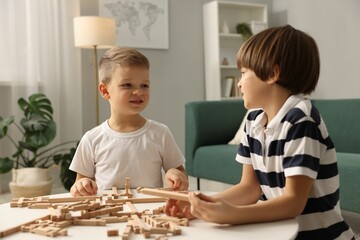Fototapeta premium Cute brothers playing with wooden construction set at table indoors