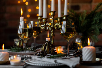 Rustic elegant table decor for christmas family dinner. Center piece with white candle, pine cone, fir tree branches. Zero waste eco-friendly home decoration. Cozy atmosphere, wooden background.