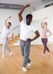 Obraz premium Adult african american man practicing ballet dance moves during group class in choreographic studio