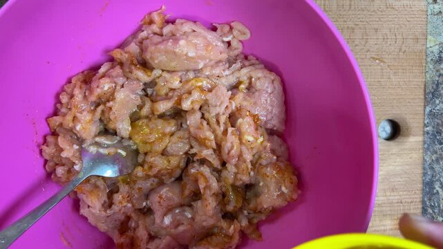 Adding fried onions to raw ground chicken in a bowl. The process of making chicken frikadelles. Top view.