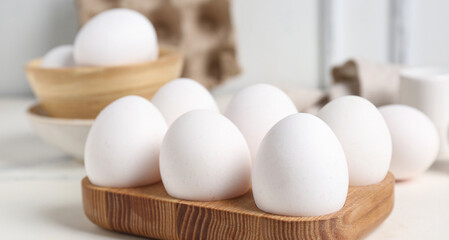 Wooden holder with raw chicken eggs on white background