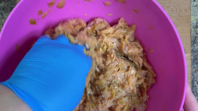 Mixing minced chicken in a bowl with your hand. Making chicken frikadelles. Top view.
