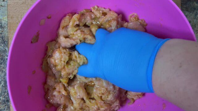 Mixing minced chicken in a bowl with your hand. Making chicken frikadelles. Top view.