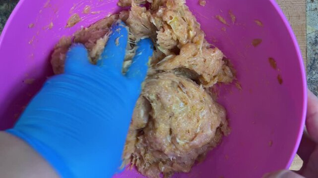 Mixing minced chicken in a bowl with your hand. Making chicken frikadelles. Top view.