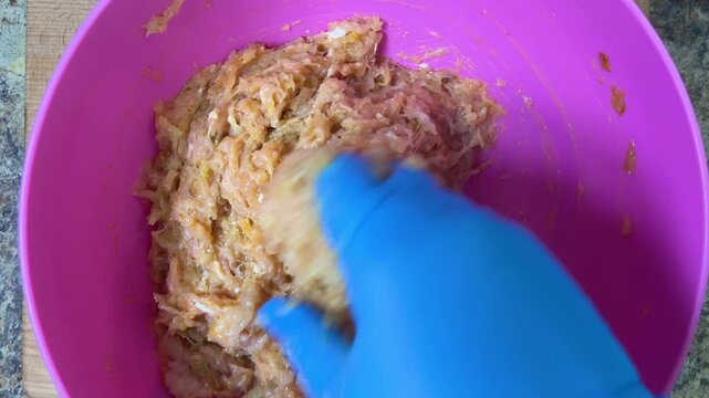 Mixing minced chicken in a bowl with your hand. Making chicken frikadelles. Top view.
