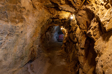 Exploring the historic underground gold mine tunnel illuminated by dim lights, revealing rugged...