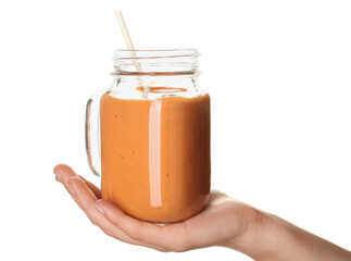Female hand with mason jar of orange smoothie on white background
