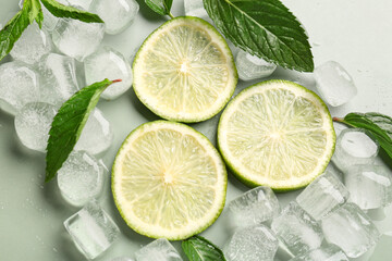 Lime slices with ice cubes and mint on green background