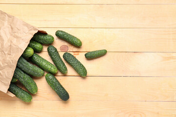 Paper bag with fresh cucumbers on wooden background