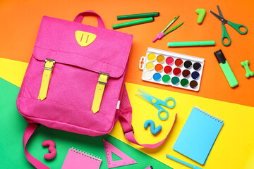 Composition with colorful school backpack and different stationery on color background