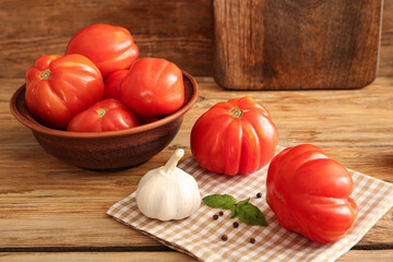 Bowl with fresh ripe tomatoes and different spices on wooden background