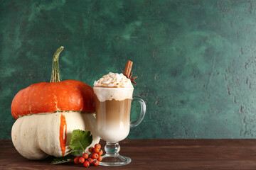 Glass cup of tasty pumpkin latte with cinnamon and star anise on wooden table