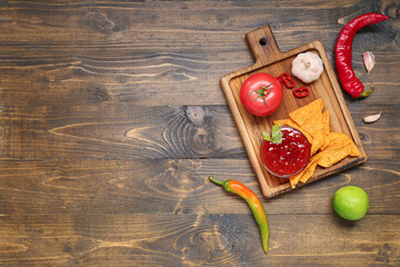 Bowl with tasty salsa sauce, ingredients and nachos on wooden background