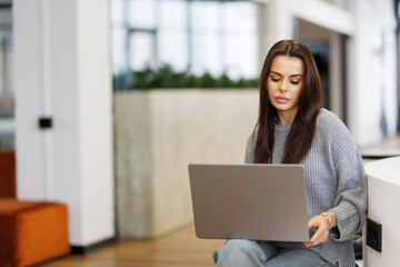 Naklejka premium Young woman smiling while working with laptop in office