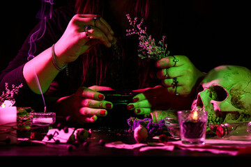 Witch with herbs at dark table, closeup