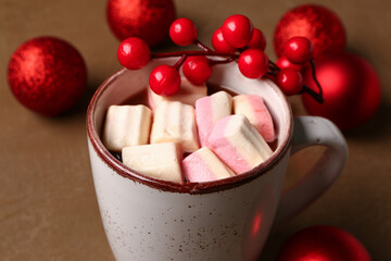 Cup of hot chocolate with marshmallows, rowan and Christmas balls on brown background